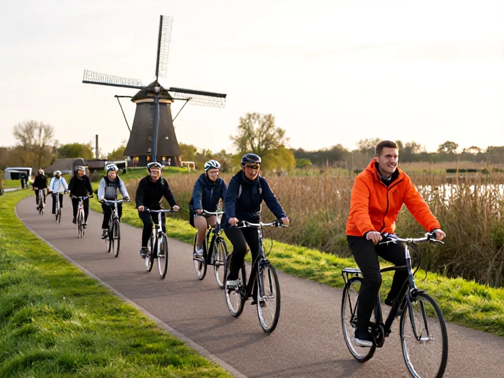 A guided bike tour group riding past a windmill